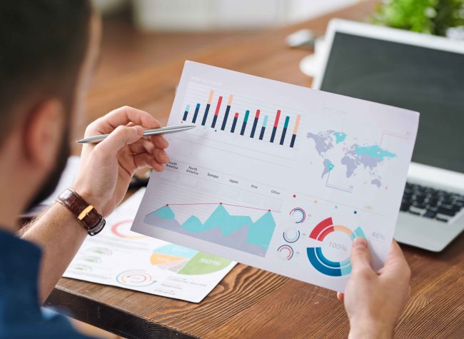 man pointing at financial chart on paper while analyzing it